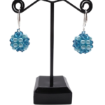 Blue crystal and aquamarine pearl cluster drop earrings displayed on black jewellery stand