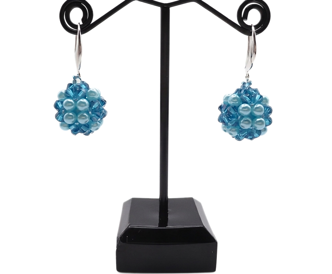 Blue crystal and aquamarine pearl cluster drop earrings displayed on black jewellery stand