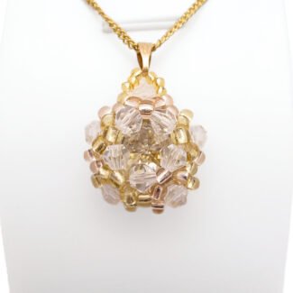 Handmade champagne crystal cluster pendant featuring a large champagne faceted centre crystal surrounded by clear crystals, golden yellow bead accents, with a gold-tone bail, displayed on a gold-tone curb chain and white jewellery stand.