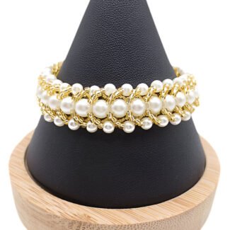 Handmade wide beaded bracelet featuring multi-sized white pearl beads woven together with gold-tone beads in a textured layered pattern, displayed on a black cone jewellery stand with wooden base