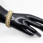 Handmade wide white pearl and gold-tone bead woven bracelet worn on a black jewellery hand mannequin, showing the full width and layered texture of the handcrafted beaded design