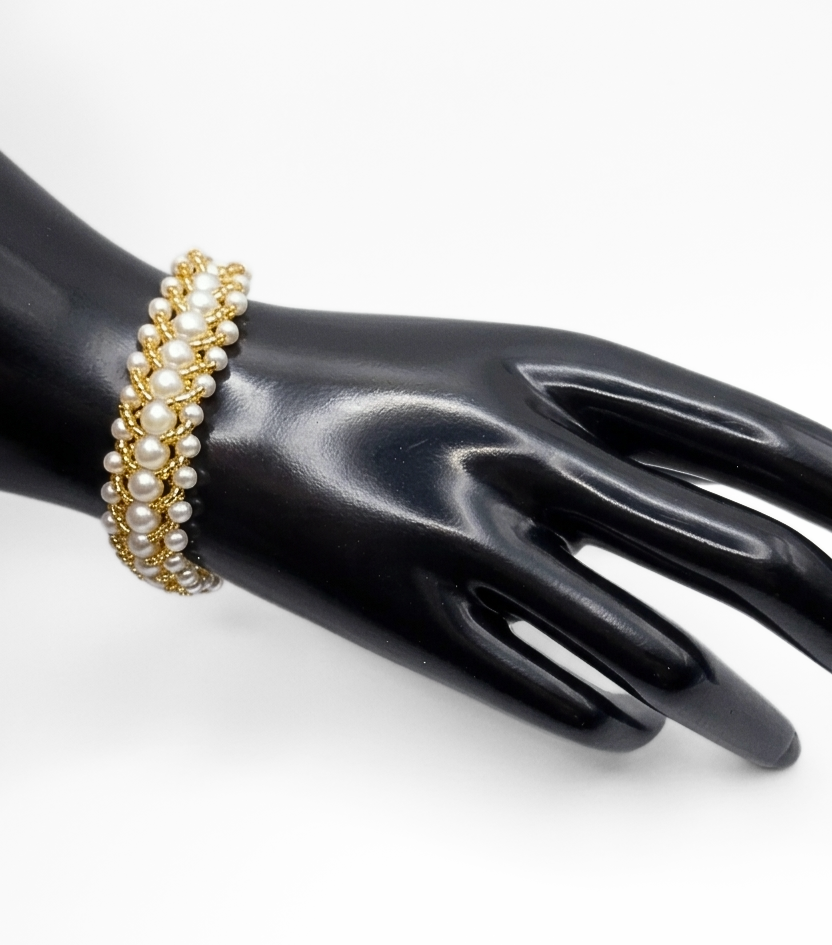 pearl-gold-bead-bracelet-wrist-display Handmade wide white pearl and gold-tone bead woven bracelet worn on a black jewellery hand mannequin, showing the full width and layered texture of the handcrafted beaded design