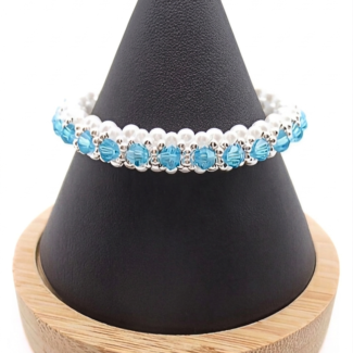 Handmade beaded bracelet featuring aquamarine blue crystal beads, white pearl beads, and silver-tone accent beads, displayed on a black cone jewelry stand with wooden base