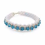 Handmade aquamarine blue crystal and white pearl stretch bracelet with silver-tone seed beads and lobster clasp closure, laid flat on white background.