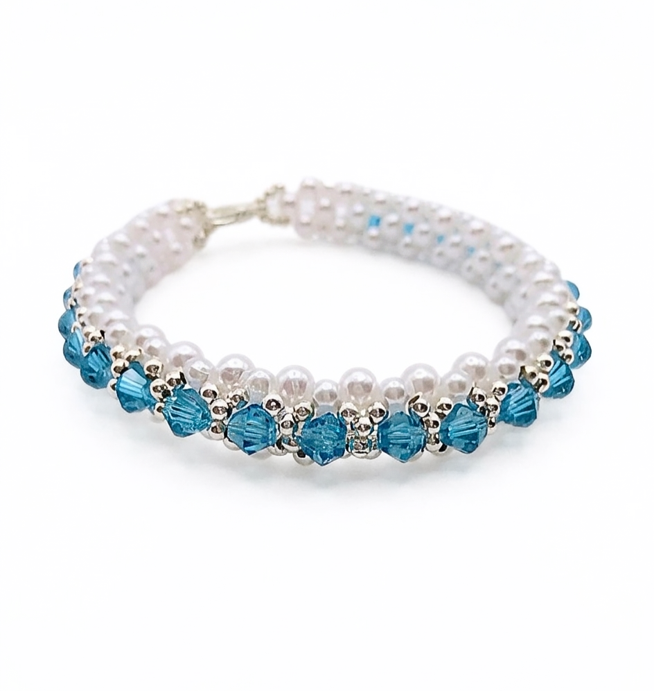 aquamarine-bracelet-main Handmade aquamarine blue crystal and white pearl stretch bracelet with silver-tone seed beads and lobster clasp closure, laid flat on white background.