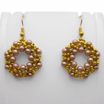 Handmade light brown faux pearl and gold-tone beaded open hoop drop earrings displayed on a white earring stand, showcasing the full woven circular lattice shape and gold fish hook ear wires