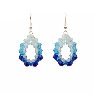 Handmade blue ombre crystal oval dangle earrings, gradient colours from light blue to cobalt blue on an open frame beaded with silver ear wires. Shown against a white flat display background.