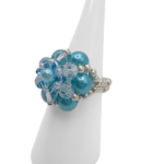 Handmade aquamarine pearl and crystal cluster ring on white cone ring stand — sky blue pearl beads, clear crystals, and silver-tone seed bead band