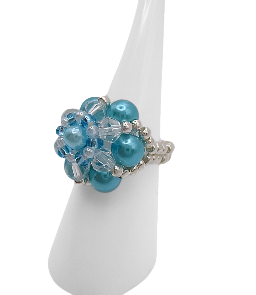 Handmade aquamarine pearl and crystal cluster ring on white cone ring stand — sky blue pearl beads, clear crystals, and silver-tone seed bead band