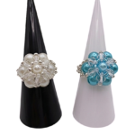 Two handmade pearl cluster cocktail rings displayed side by side on black and white cone stands — white pearl ring on left, aquamarine blue pearl ring on right, both with clear crystal and silver-tone accents