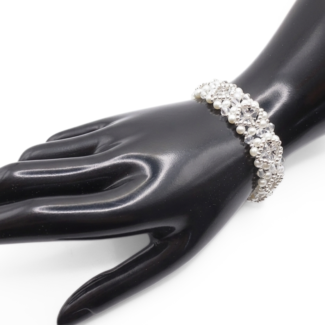 Bridal bracelet featuring white pearls and clear faceted crystals with silver-tone bead accents in a repeating floral pattern, shown on a black mannequin hand against a white background.