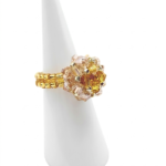 Handmade beaded ball ring with golden topaz and blush champagne crystals on gold beaded band, shown on white ceramic ring display cone