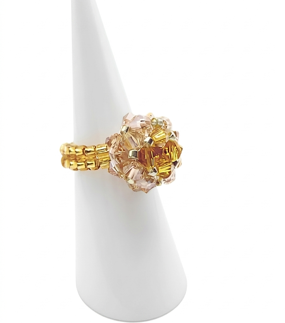 champagne-crystal-ring-side-view Handmade beaded ball ring with golden topaz and blush champagne crystals on gold beaded band, shown on white ceramic ring display cone