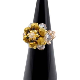 Three-quarter view of handmade metallic gold and champagne crystal cluster cocktail ring on black cone ring stand, showing domed floral bead arrangement and warm golden tones
