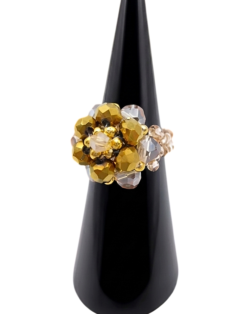 Three-quarter view of handmade metallic gold and champagne crystal cluster cocktail ring on black cone ring stand, showing domed floral bead arrangement and warm golden tones