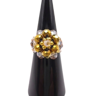Handmade beaded cocktail ring featuring a domed cluster of metallic gold and champagne crystal beads in a floral design, displayed on a black cone ring stand against a white background