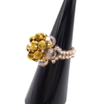 Side view of handmade gold and champagne crystal cluster ring on black cone ring stand, showing double-row champagne and silver seed bead band and domed crystal top