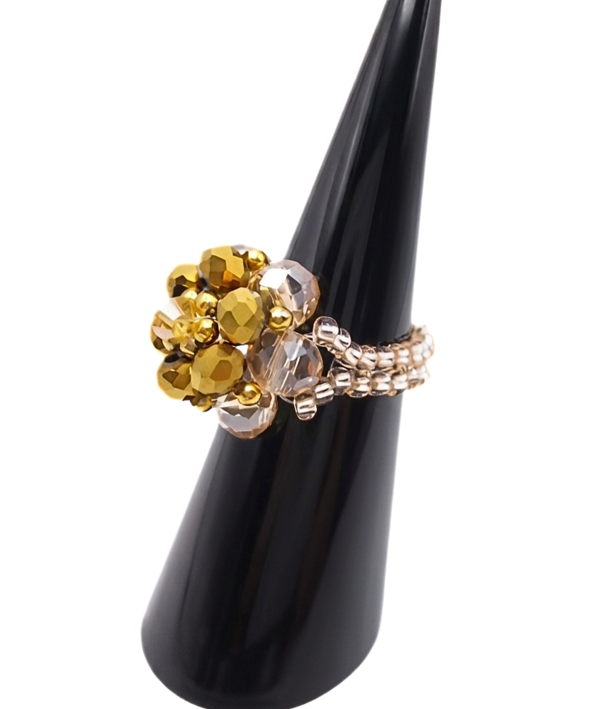 Side view of handmade gold and champagne crystal cluster ring on black cone ring stand, showing double-row champagne and silver seed bead band and domed crystal top
