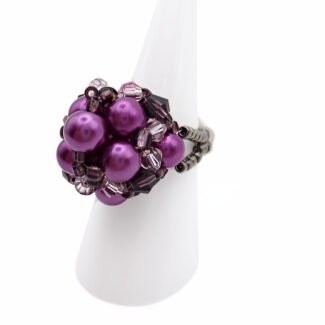 Side view of handmade purple pearl cluster ring with violet crystal beads and beaded band on white display stand