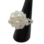 Profile view of white pearl cluster ring with clear crystal beads and silver beaded stretch band on black ring stand - handmade bridal jewellery.