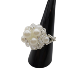 Side view of white pearl cluster ring with clear crystal beads and silver beaded stretch band on black ring stand - handmade bridal jewellery.