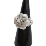 Side view of a handmade beaded cluster ring with white pearl beads, faceted light grey crystal beads, and silver-tone accents on a stretchy band, displayed on a black ring cone