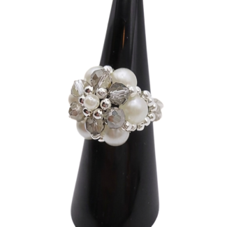 Side view of a handmade beaded cluster ring with white pearl beads, faceted light grey crystal beads, and silver-tone accents on a stretchy band, displayed on a black ring cone