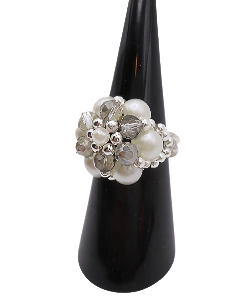 pearl-crystal-ring-grey-size Side view of a handmade beaded cluster ring with white pearl beads, faceted light grey crystal beads, and silver-tone accents on a stretchy band, displayed on a black ring cone