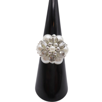 Handmade cluster ring featuring white pearl beads, faceted light grey crystal beads, and silver-tone metal accents, displayed on a black ring cone, shown against a white background