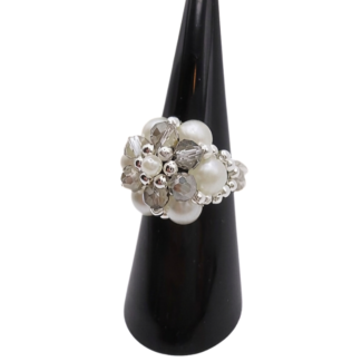 Side view of a handmade beaded cluster ring with white pearl beads, faceted light grey crystal beads, and silver-tone accents on a stretchy band, displayed on a black ring cone
