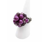 Side view of handmade purple pearl cluster ring with violet crystal beads and beaded band on white display stand