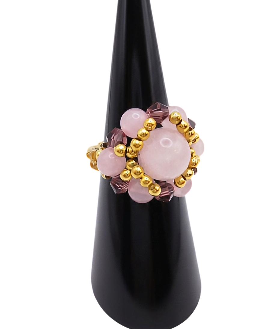 Side view of a handmade rose quartz beaded cluster ring with purple crystal beads and gold-tone accent beads on a stretch band, displayed on a black ring cone