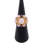 Handmade cluster ring featuring a large rose quartz center bead, smaller rose quartz beads, faceted purple crystal beads, and gold-tone metal accent beads, displayed on a black ring cone