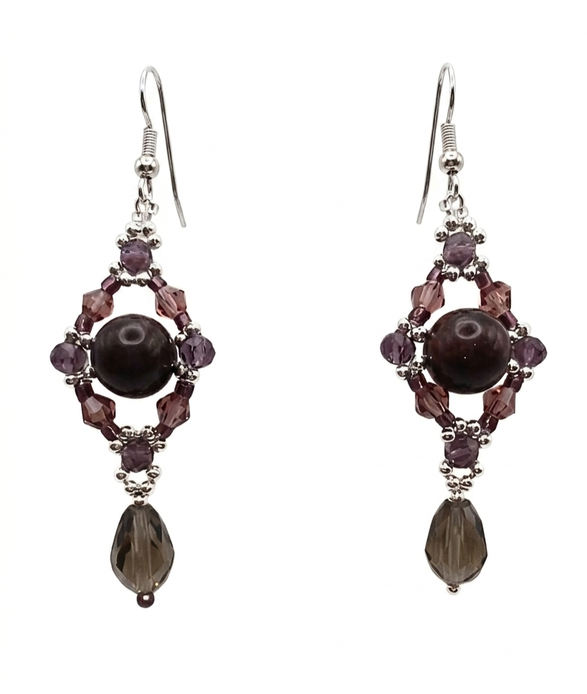 Handmade chandelier drop earrings featuring a dark tourmaline stone centre surrounded by purple and mauve crystals in a diamond frame, with a faceted smoky grey crystal teardrop and silver-tone ear wires, on white background.