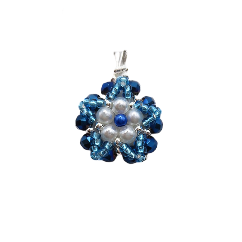 Handmade floral pendant featuring white pearls and a blue pearl centre accent surrounded by metallic blue crystals and aquamarine bead detailing, with a silver-tone bail, photographed on a white background.