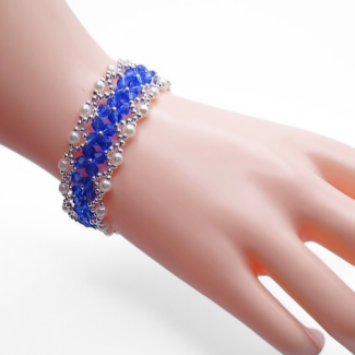 Handmade elegant royal blue crystal and white pearl bracelet with silver-tone bead accents in a repeating diamond weave pattern, shown worn on a mannequin wrist against a white background.