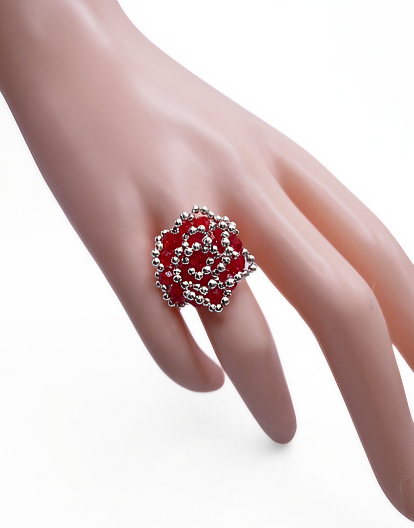 rose-crystal-ring-hand-display Front view of handmade red crystal and silver beaded cocktail ring with spiral rose design displayed on a white cone ring stand, showing intricate woven bead pattern