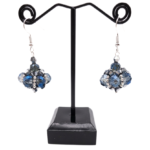 Handmade cluster drop earrings featuring translucent blue and smoky grey crystals, metallic silver crystals with silver seed beads, displayed on a black metal earring stand with silver-toned ear wires.