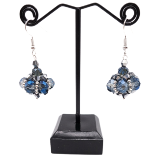 Handmade cluster drop earrings featuring translucent blue and smoky grey crystals, metallic silver crystals with silver seed beads, displayed on a black metal earring stand with silver-toned ear wires.