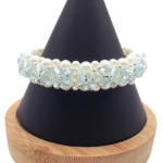 A close-up photograph of a hand-woven multi-strand beaded bracelet on a black display hand against a plain white background. The bracelet is made with white faux pearls and faceted light blue crystal beads arranged in a floral weave with silver bead accents.
