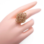 Handmade champagne crystal cluster ring worn on mannequin hand - large statement cocktail ring with gold beads and a hidden large crystal centre.