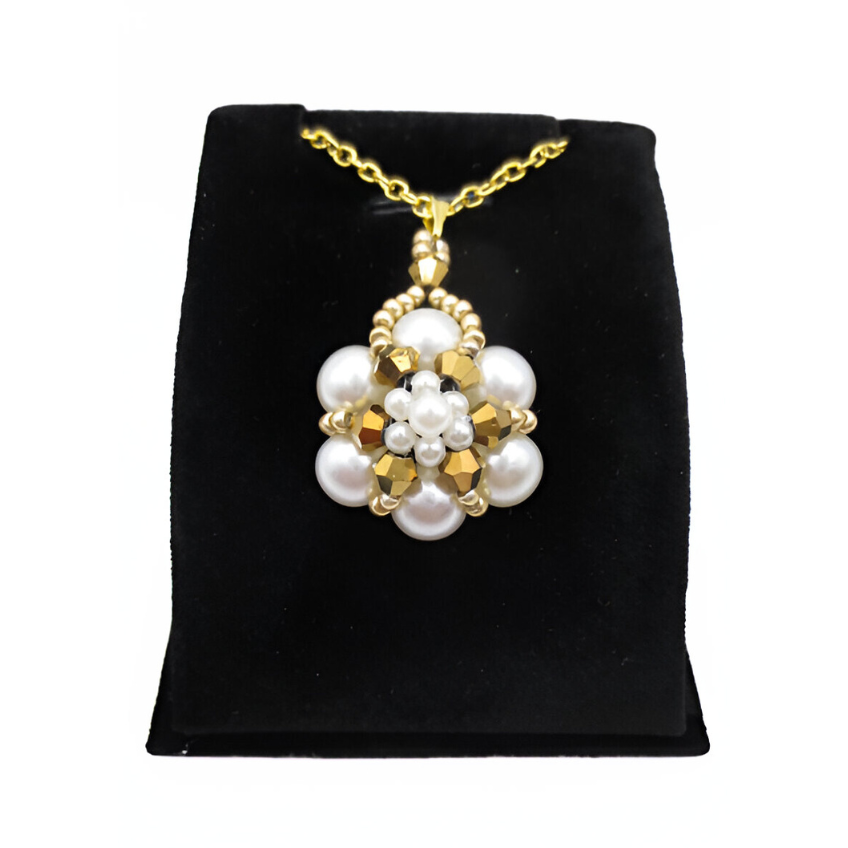 pearl-pendant-gold-crystals-stand Handmade white pearl and gold-tone crystal pendant featuring off-white pearls arranged in a floral cluster with metallic gold crystal accents, a pearl centre detailing and a gold-tone bail, shown against a black display stand.