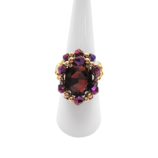 Handmade statement purple crystal cocktail ring with gold-tone beads on white ring display stand, shown against a white background.