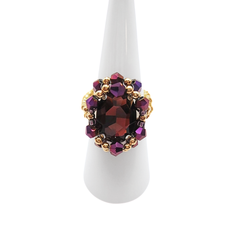 Handmade statement purple crystal cocktail ring with gold-tone beads on white ring display stand, shown against a white background.