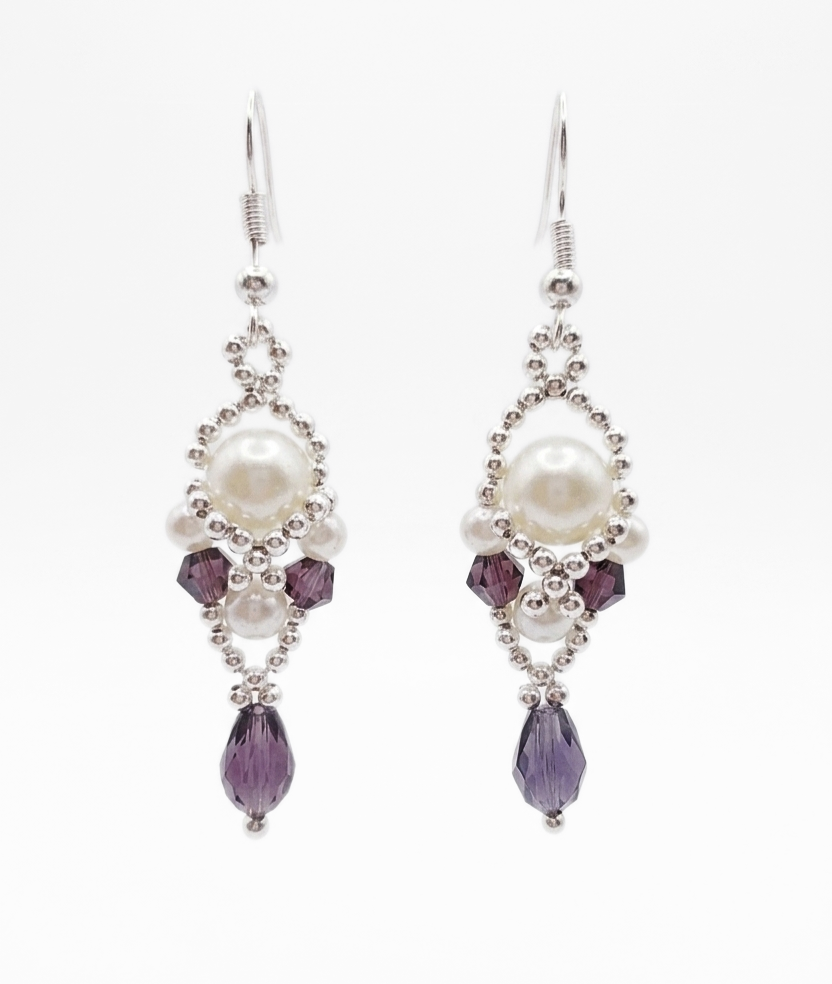 purple-drop-pearl-earrings Handmade purple amethyst crystal and white pearl dangle earrings with silver-tone beaded frame and teardrop crystal, shown against a white background