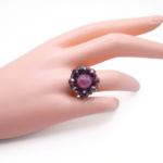 Rose pink tourmaline and purple AB crystal beaded statement ring worn on a middle finger, showing size and wearability of handmade floral cocktail ring against a light background
