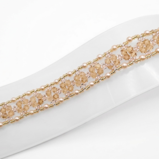 Handmade champagne crystal bracelet featuring faceted crystals and small champagne pearls woven with gold bead accents in an open lattice diamond pattern, displayed flat on a white jewellery stand showing full length and gold-tone lobster clasp with extension chain against a white background.