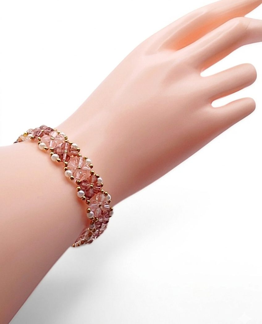 Handmade pink and purple crystal bracelet featuring light pink and purple faceted crystals in a repeating four-petal flower pattern with white pearl and gold seed bead accents, shown worn on a mannequin wrist and hand against a white background.