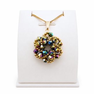 Iridescent crystal pendant necklace with gold-coloured chain and bail, displayed on a white jewellery stand, showcasing multi-colored metallic beadwork design