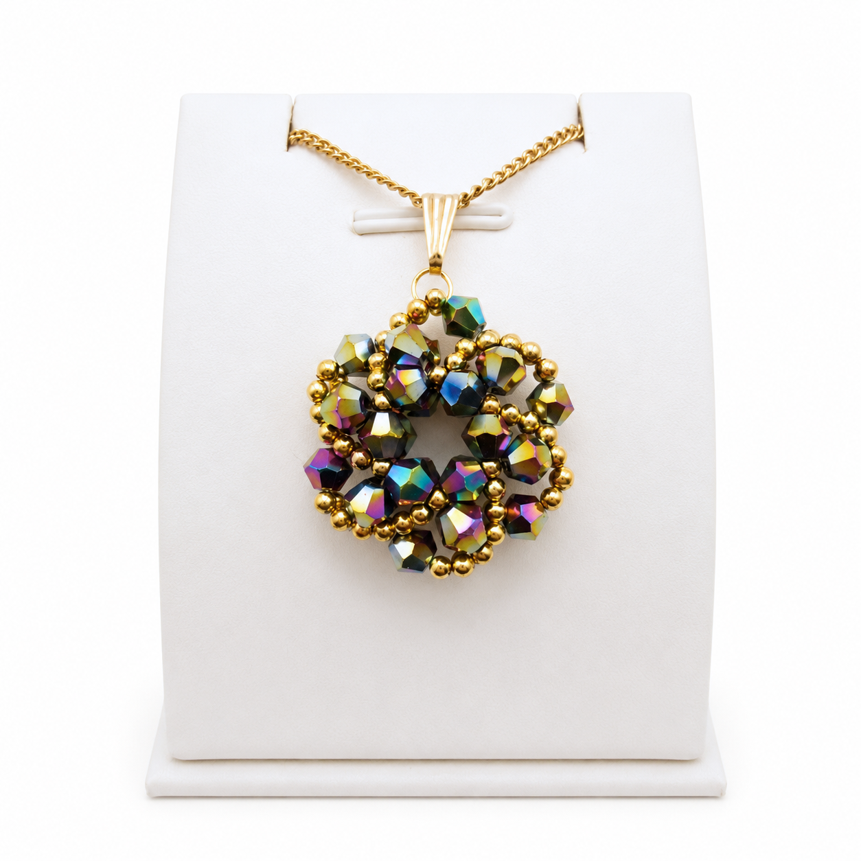 Iridescent crystal pendant necklace with gold-coloured chain and bail, displayed on a white jewellery stand, showcasing multi-colored metallic beadwork design